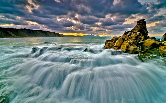 Ocean waves crashing on rocks at sunset