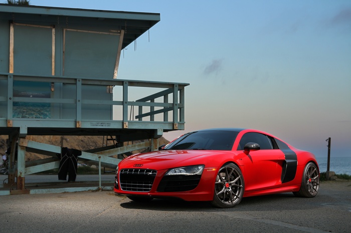 Red Audi R8 by a lifeguard tower at the beach
