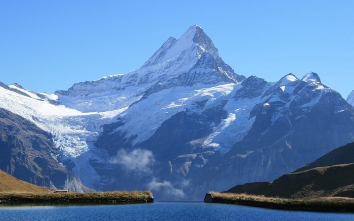 Snow-capped mountain range with a lake in the foreground