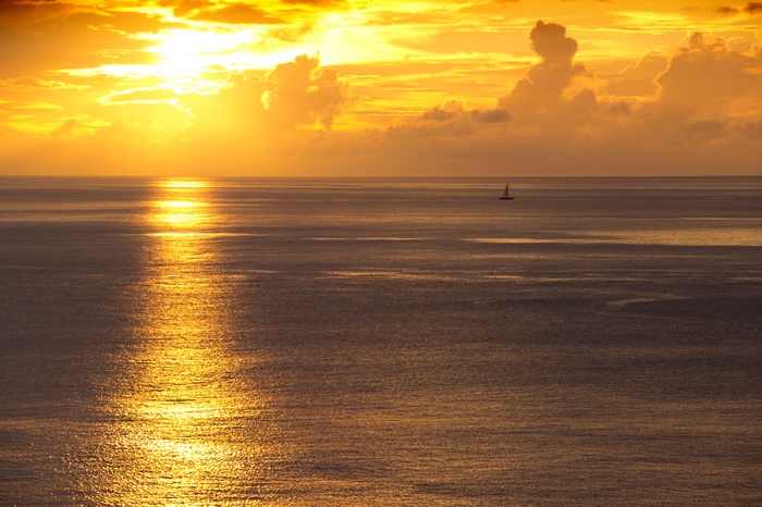 Sunset over the ocean with a sailboat