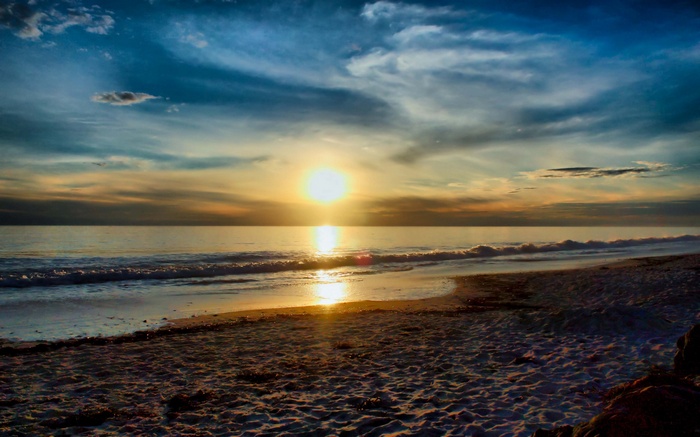 Sunset over the ocean with waves on the beach