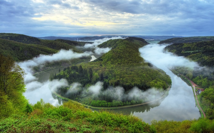 Meandering river through forested hills with morning mist