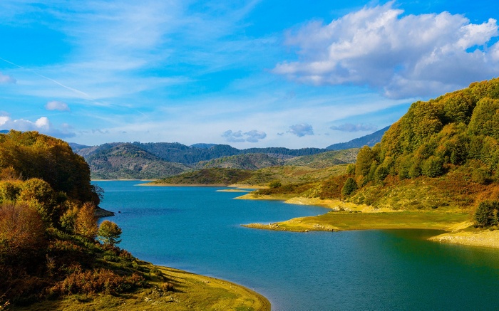 Turquoise lake surrounded by autumn hills under a blue sky