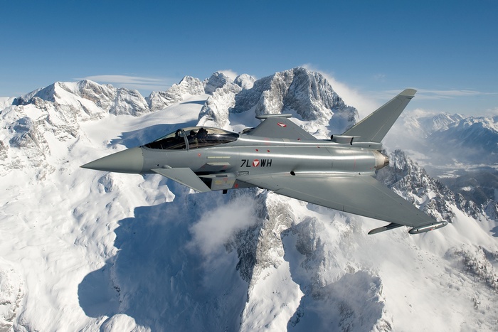 Eurofighter Typhoon flying over snow-covered mountains