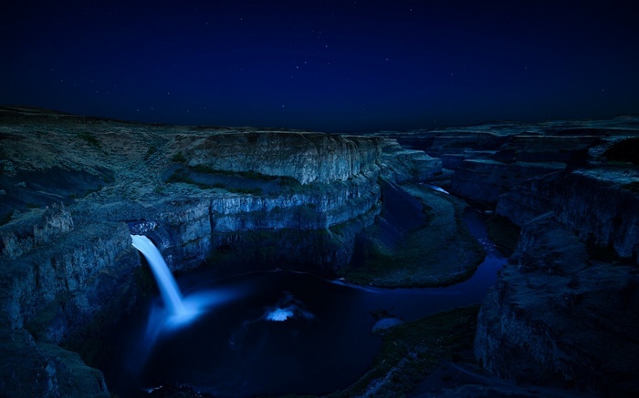 Waterfall in a canyon at night under stars
