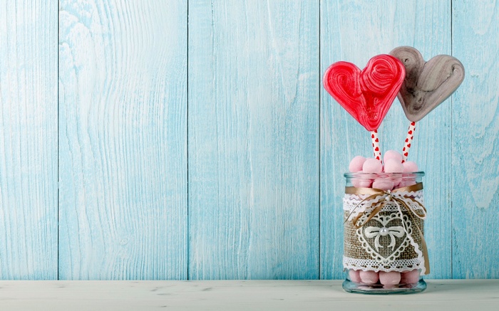 Heart-shaped lollipops and marshmallows in a decorated jar