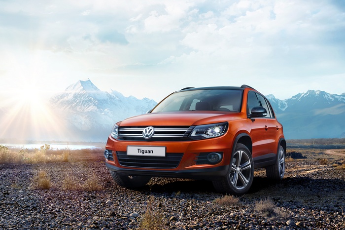 Orange Volkswagen Tiguan parked on rocky terrain with mountains