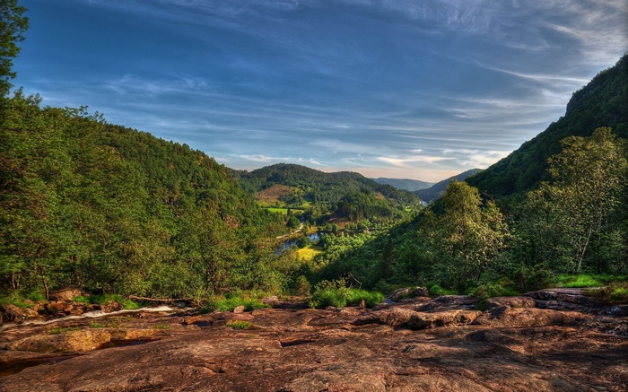 Valley with river and forested hills under a cloudy sky