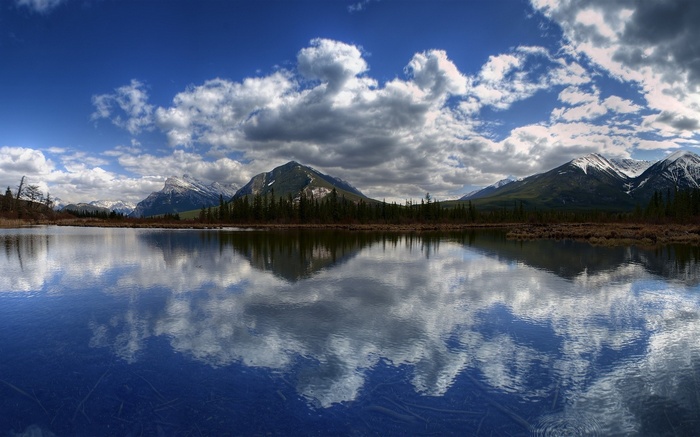 Mountain lake reflection with clouds and snow-capped peaks