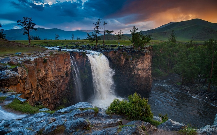 Waterfall cascading over rocky cliffs at sunset