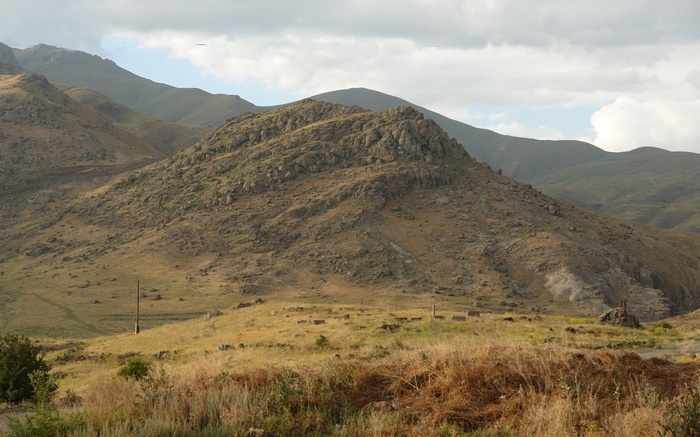 Rocky mountain landscape with dry grass and clouds
