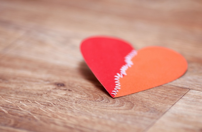 Broken heart with stitches on wooden surface