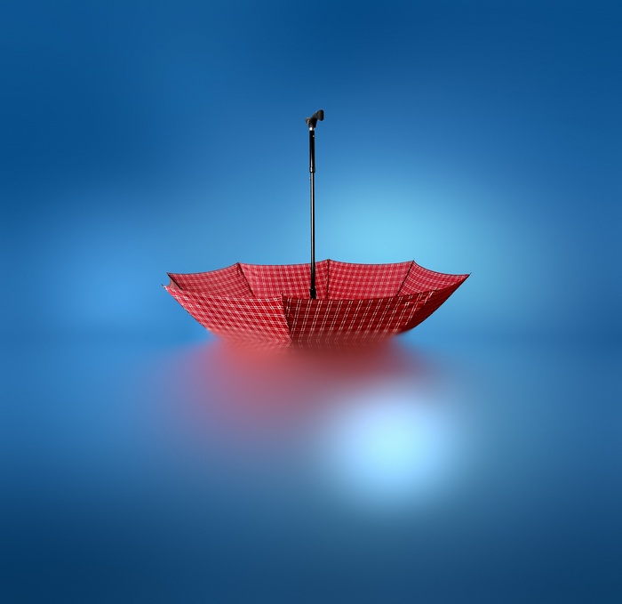 Red umbrella floating upside down on blue surface