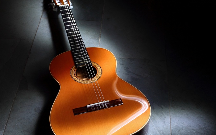Acoustic guitar on a dark floor