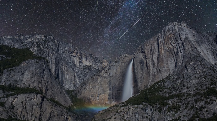 Waterfall under starry sky with meteor shower