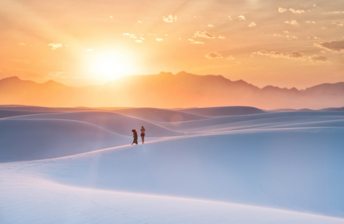 People and dog on sand dunes at sunset in White Sands, New Mexico