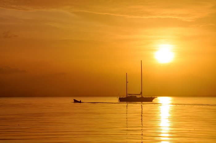 Sailboat and dinghy at sunset