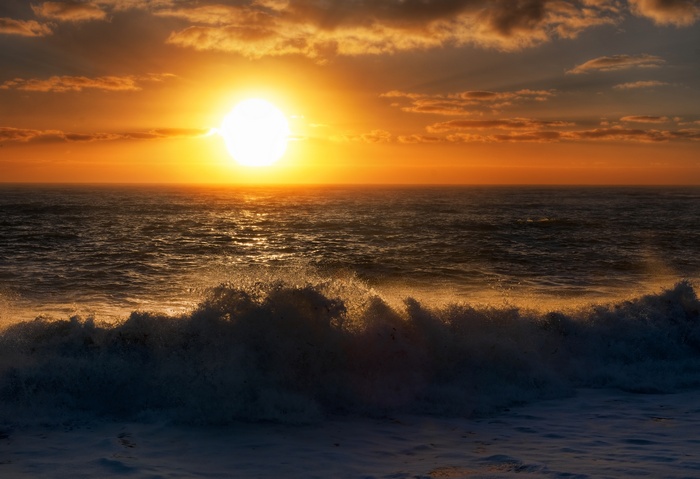 Sunset over the Tasman Sea with waves crashing on the beach