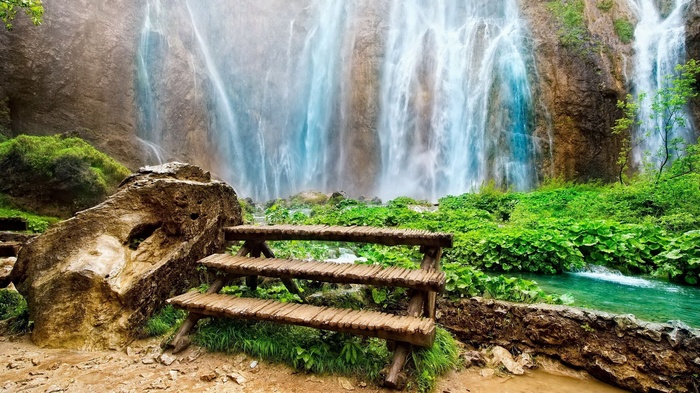 Wooden bench in front of a cascading waterfall