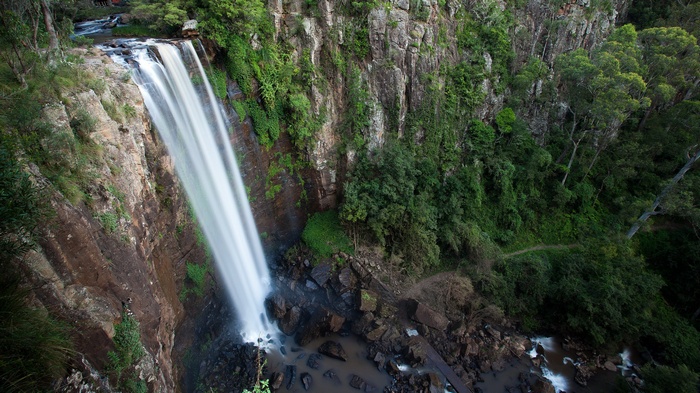 Waterfall cascading down a rocky cliff face surrounded by trees