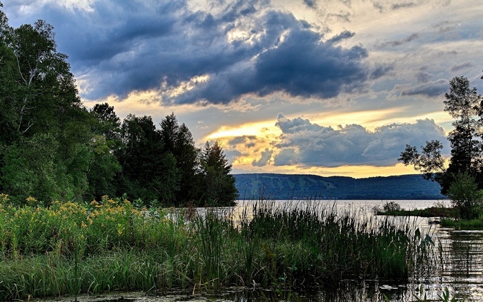 Sunset over a lake with trees and clouds