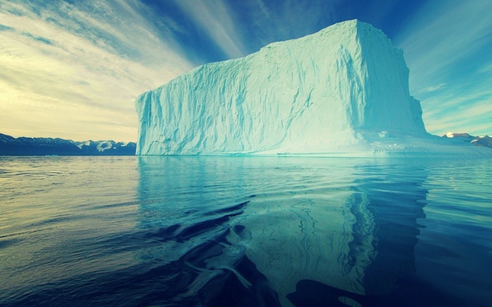 Massive iceberg floating in the ocean under a cloudy sky