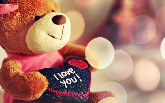 Teddy bear holding a heart with "I love you!"