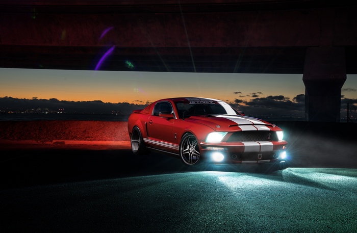 Red Shelby GT500 Ford Mustang under a bridge at dusk