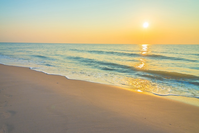 Sunset over the ocean waves on a sandy beach