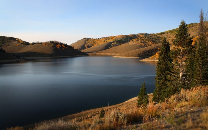 Lake surrounded by autumn hills and evergreen trees