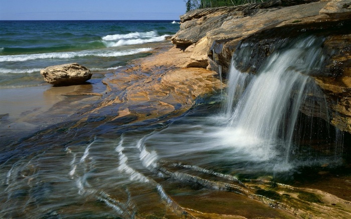 Waterfall cascading over layered rocks into a lake