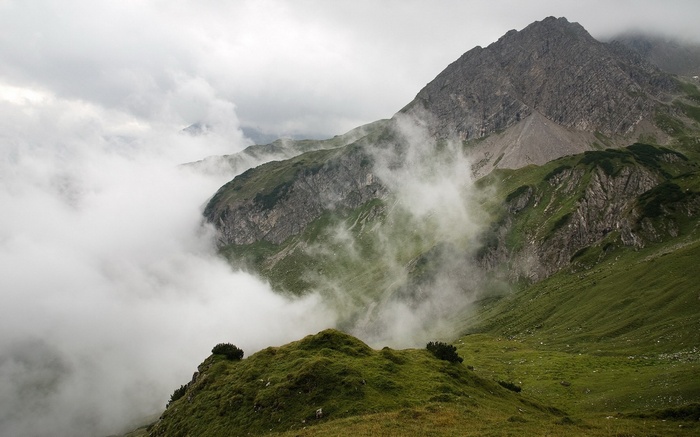 Misty mountains with green slopes and rocky peaks