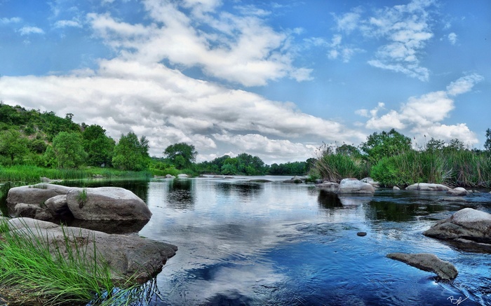 River with rocks and trees under a cloudy sky