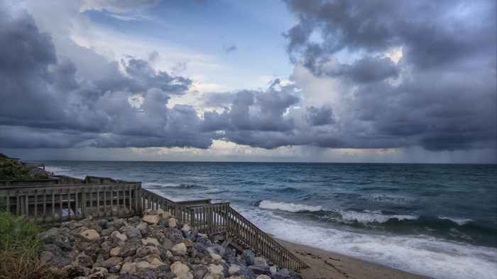 Wooden boardwalk stairs leading to a stormy beach