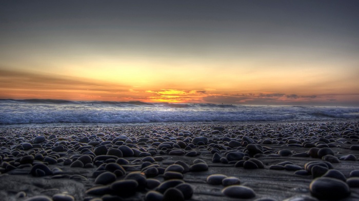 Pebble beach at sunset with ocean waves