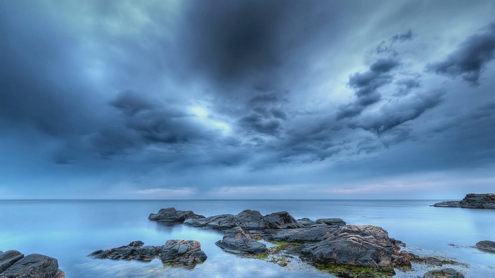 Stormy clouds over a rocky coastline and calm sea