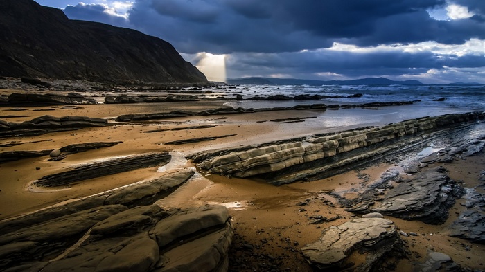Rocky beach with dramatic clouds and ocean waves