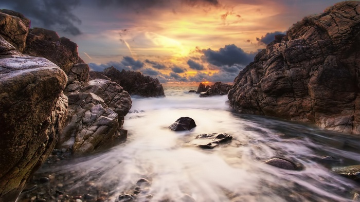 Rocky coastline with ocean waves at sunset