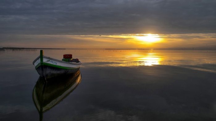 Boat on calm water at sunset