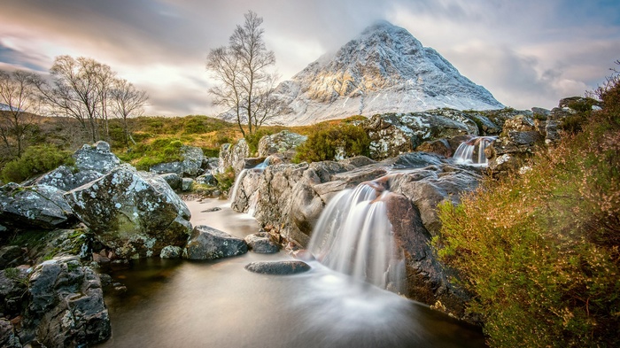 Waterfall cascading over rocks with snow-capped mountain in background