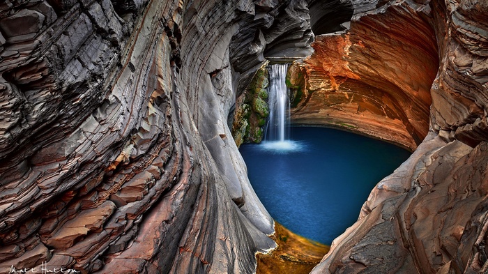 Waterfall cascading into a blue pool in a rocky gorge