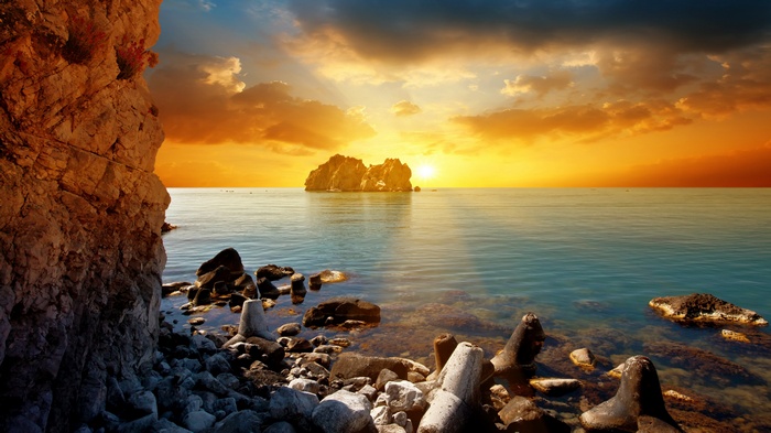 Rocky coastline at sunset with island in the sea