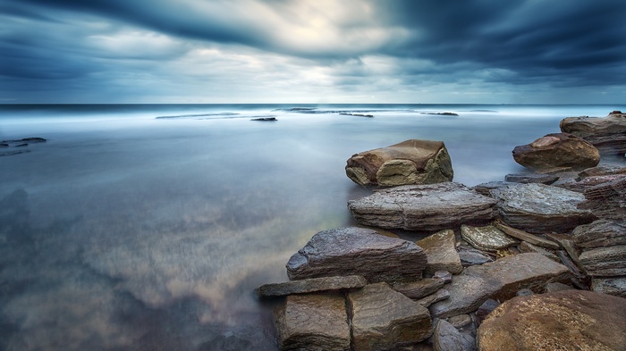 Long exposure of rocky coastline and ocean under cloudy sky
