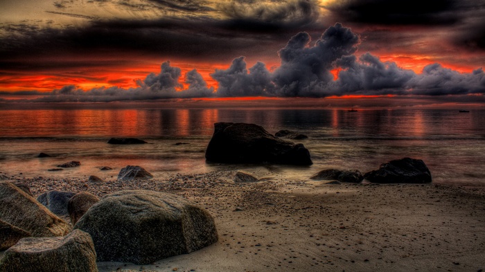 Dramatic sunset over a rocky beach with calm ocean