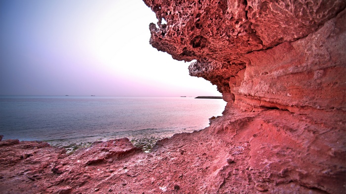 Red rock formations on a beach at sunset