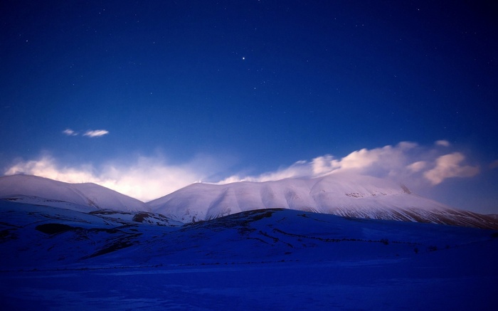 Snowy mountains under a starry night sky