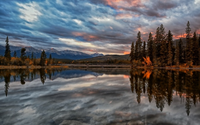 Lake reflection of mountains and trees at sunset