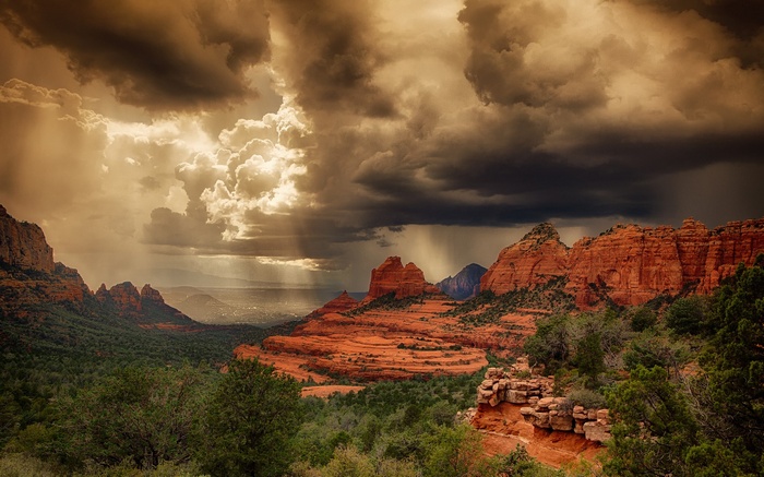 Stormy sky over red rock formations and green forest