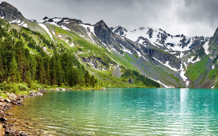 Turquoise mountain lake with snow-capped peaks and pine forest
