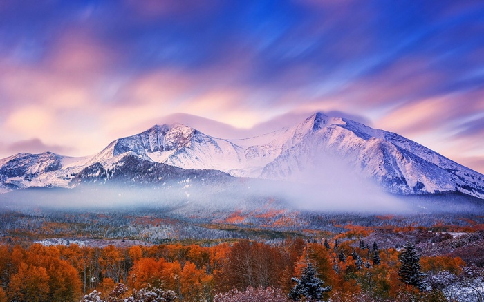 Snow-capped mountains at sunrise with autumn trees
